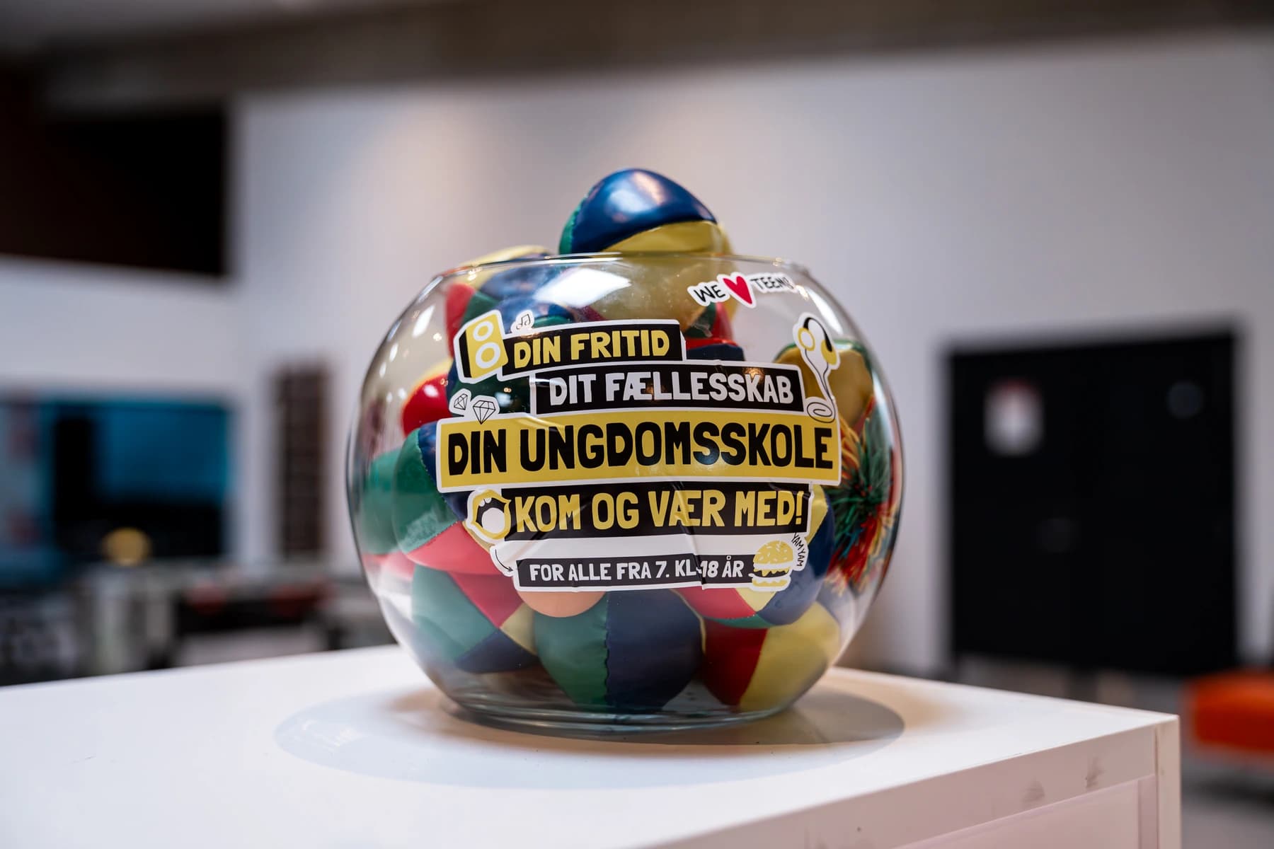 Glasskål med farverige bolde og Ungdomsskole-stickers — kom og vær med
