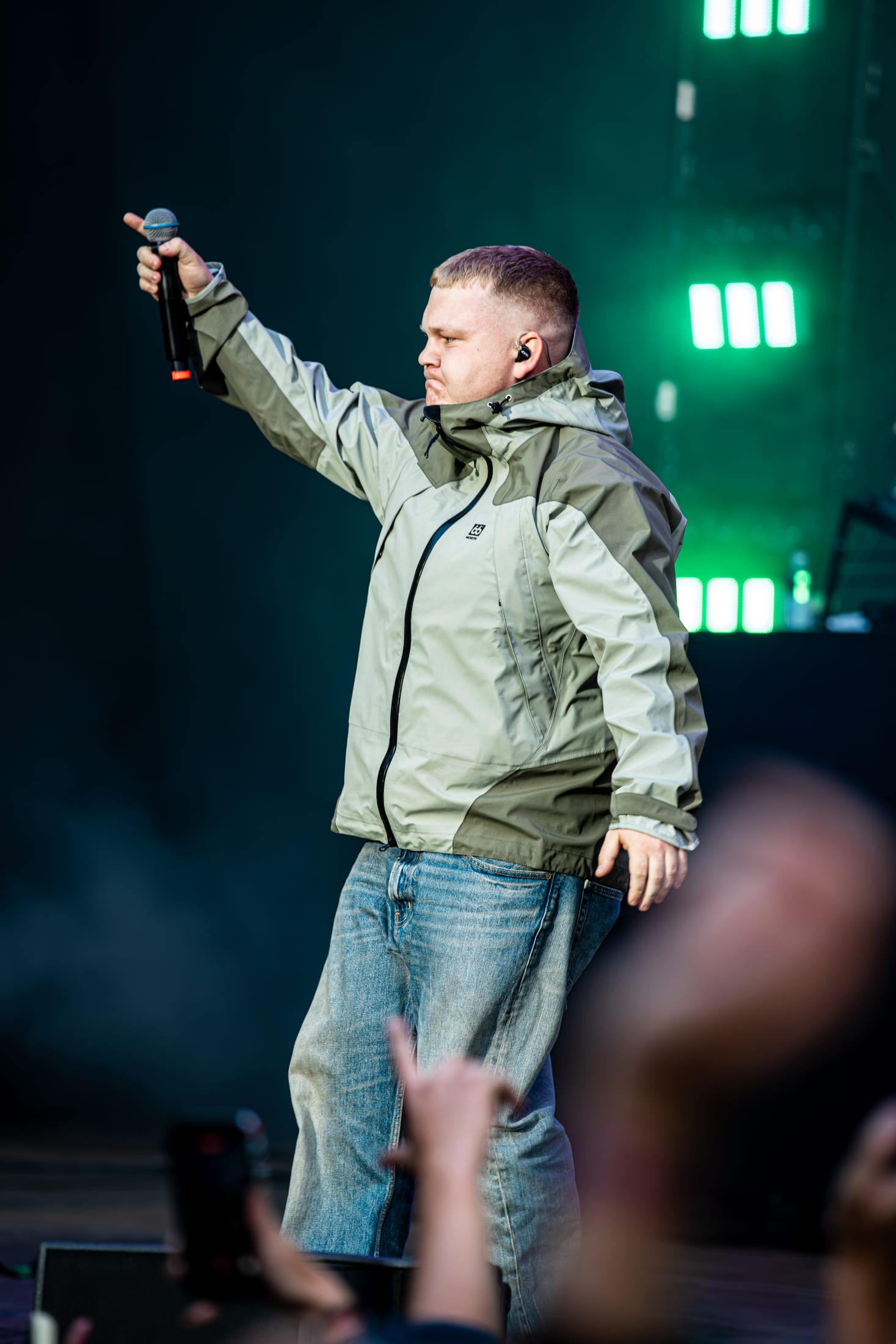 Thor Farlov med mikrofonen højt på Smukfest under grønt scenelys