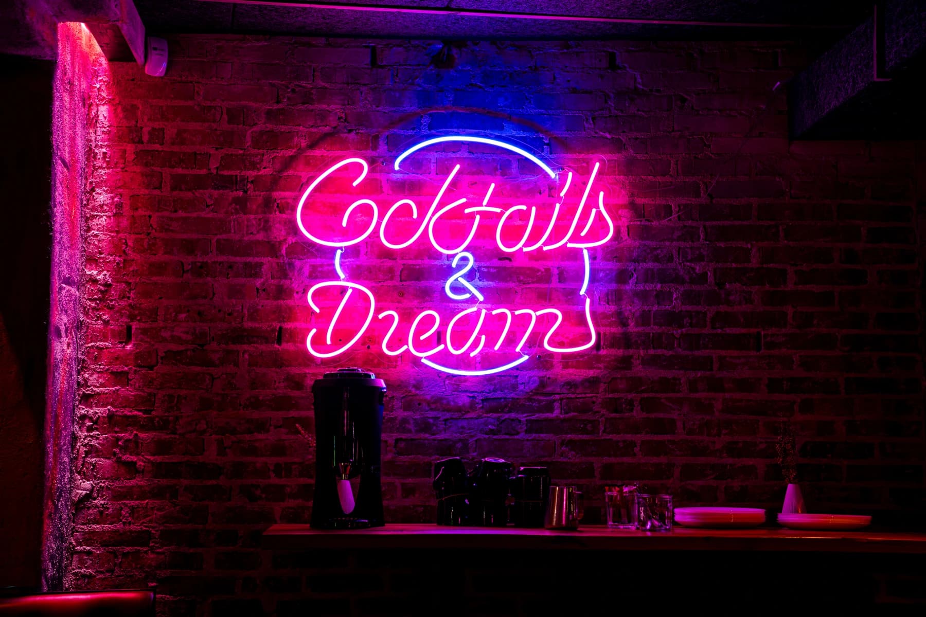 Pink neonskilt med Cocktails & Dreams-logo over bar med murstensvæg — fotograf i Ribe