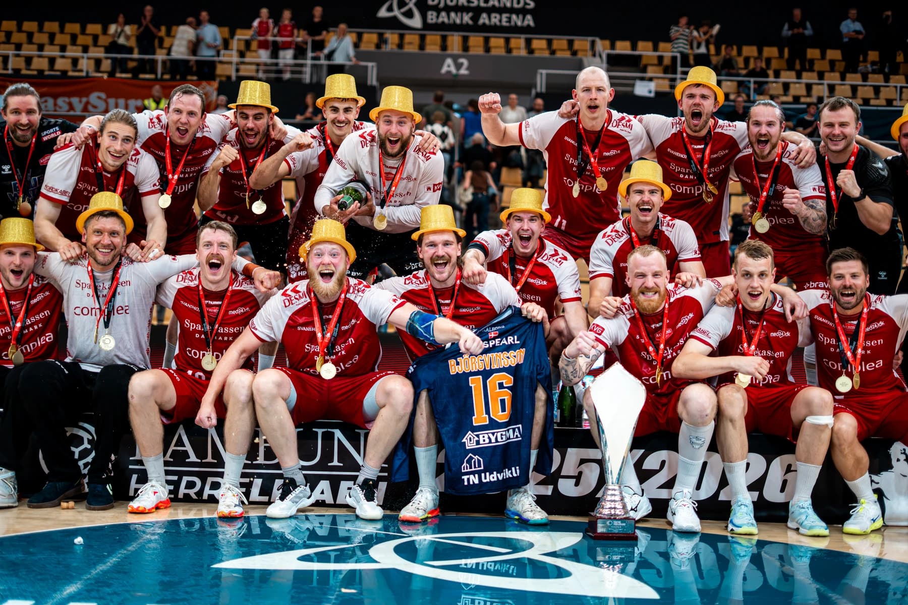 GOG Håndbold fejrer sejr i klubtrøjer med pokal og guldhatte — fotograf i Grenaa